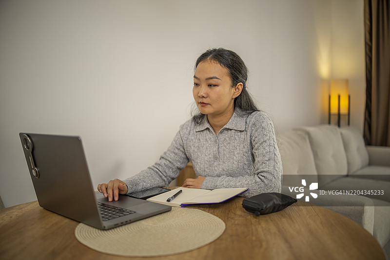 可爱的亚洲女性坐在餐厅的桌子旁上网。图片素材