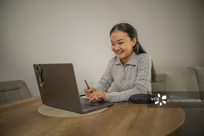 可爱的亚洲女性坐在餐厅的桌子旁，正在个人组织器上写字并上网。图片素材