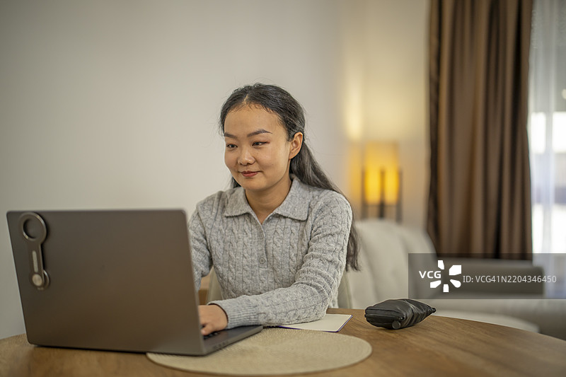 可爱的亚洲女性坐在餐厅的桌子旁上网。图片素材