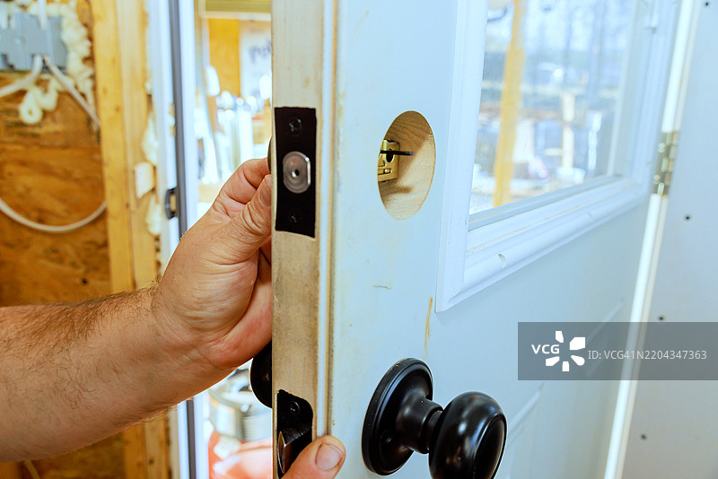在下午的工作坊里，手将门把手安装到复古门上图片素材