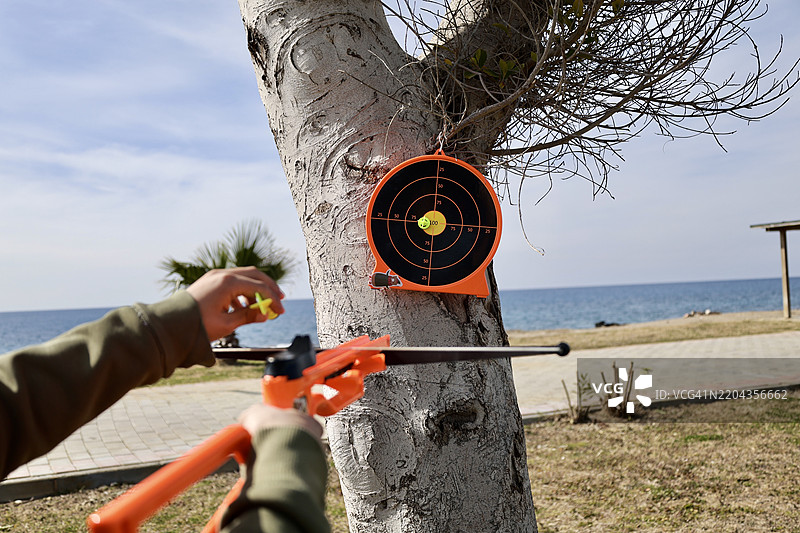 在海边的天空下，男人的手正在切割金属。图片素材