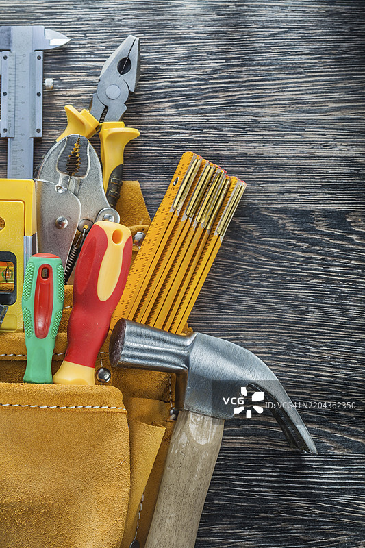 皮革工具带与木板上的建筑工具，垂直视图图片素材