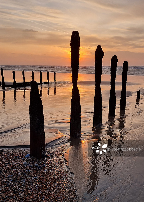 日落时分，海滩上人们的剪影与天空相映成趣图片素材