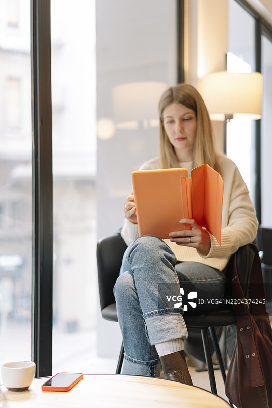 年轻女性坐在办公室的椅子上阅读书籍图片素材