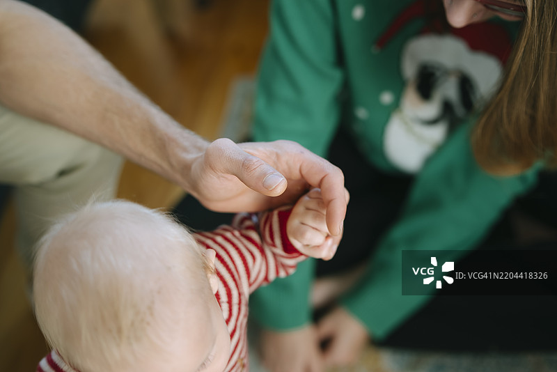 温馨时刻：婴儿温柔地握着爱护自己的父母的手，充满了关爱与呵护图片素材