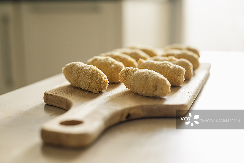 新鲜揉制和裹粉的可乐饼特写，放在木板上准备烹饪图片素材