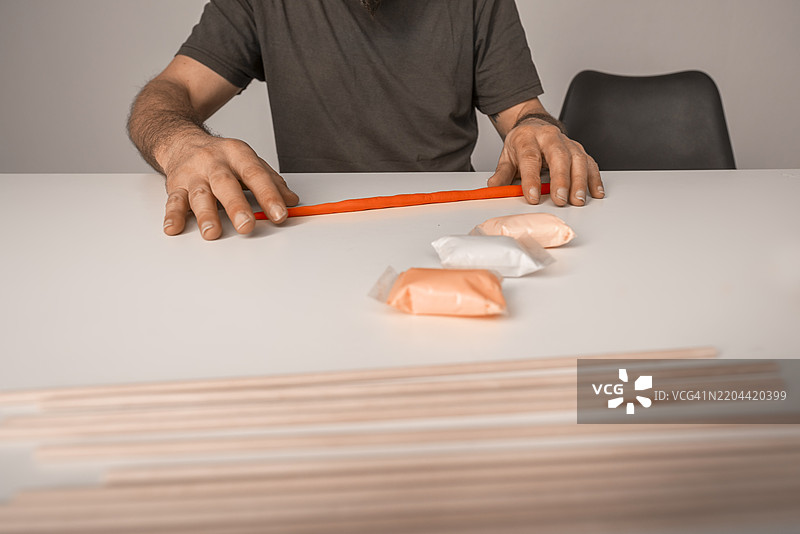 用彩色粘土制作情人节手工艺品的双手，呈现出鲑鱼色调。图片素材