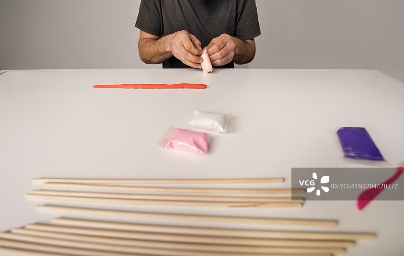 粉色调的情人节手工艺材料和双手制作工艺品的桌子，使用空气干燥彩色粘土图片素材