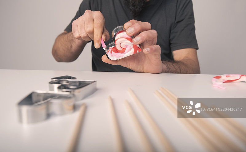 垂直视角下的双手在心形模具中捏制情人节礼物的粘土图片素材