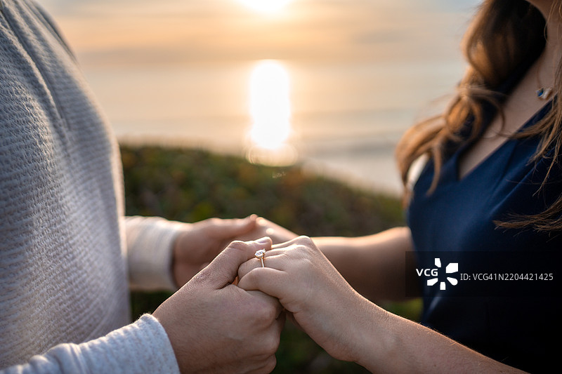 日落时分，情侣在海滩上牵手的中段画面图片素材