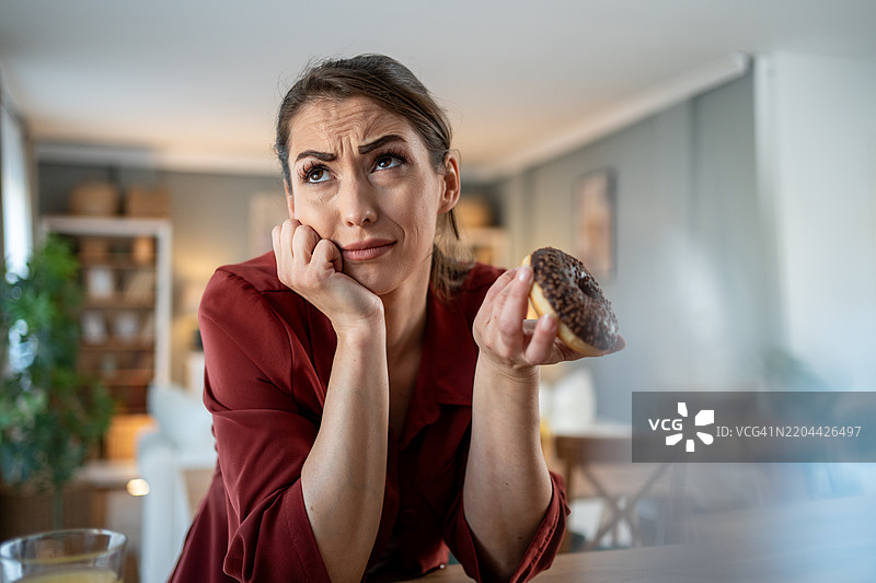 女人享用作弊餐，因吃了甜甜圈而感到内疚图片素材