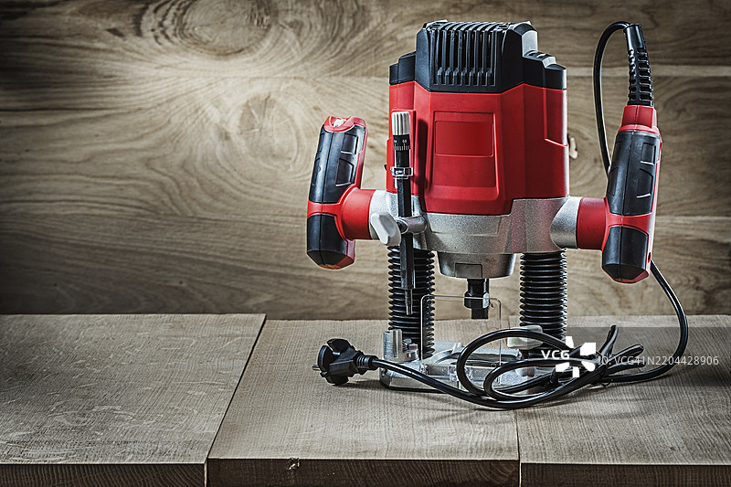 红色变速小型冲击铣刀便携式电动迷你木工路由器，背景为复古木纹图片素材