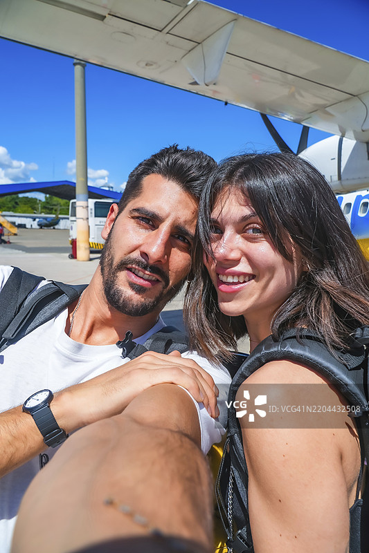 年轻的背包客情侣在机场拍摄快乐的自拍，兴奋地准备一起迎接即将到来的冒险图片素材