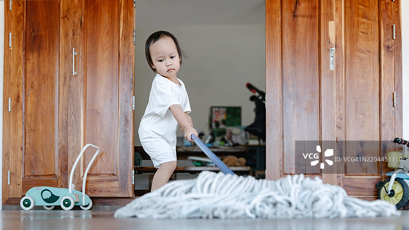 可爱的小女孩帮助妈妈用拖把清洁地板图片素材