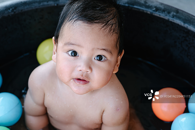 可爱的小男孩在浴缸里玩彩色球。图片素材