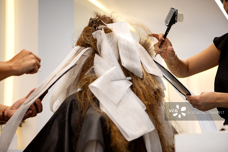 年轻女性发型师为客户进行漂发处理图片素材