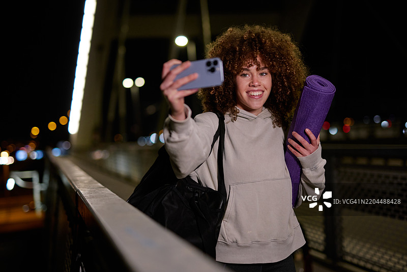 年轻女性在桥上夜间锻炼后自拍图片素材