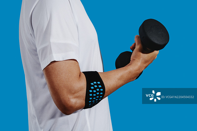 男子手持哑铃，佩戴肱骨外上髁炎手环图片素材