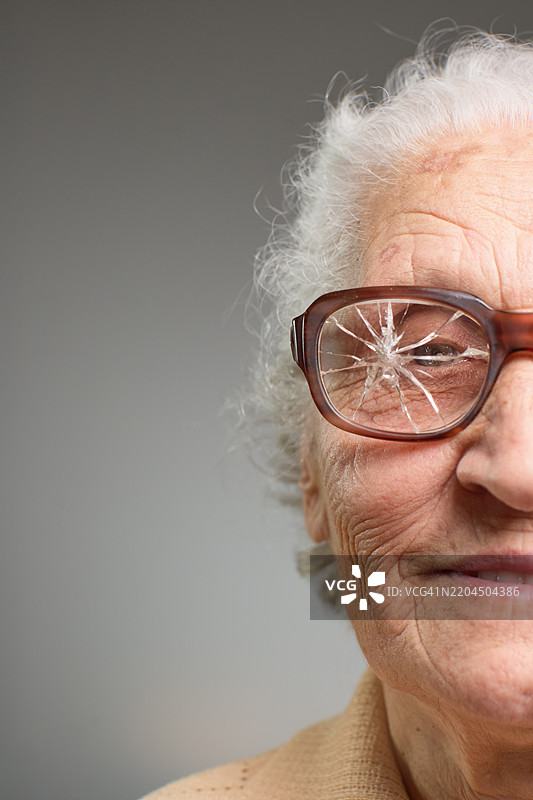 一位老年女性的特写肖像，戴着破损的眼镜图片素材