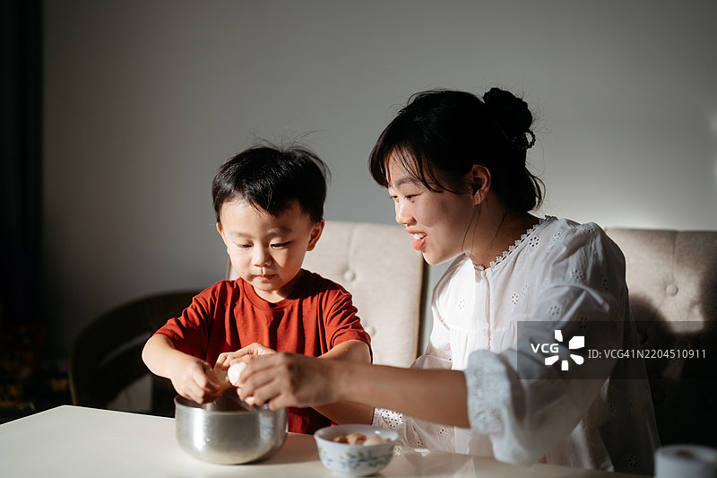 亚洲母亲教她的儿子打破鸡蛋图片素材