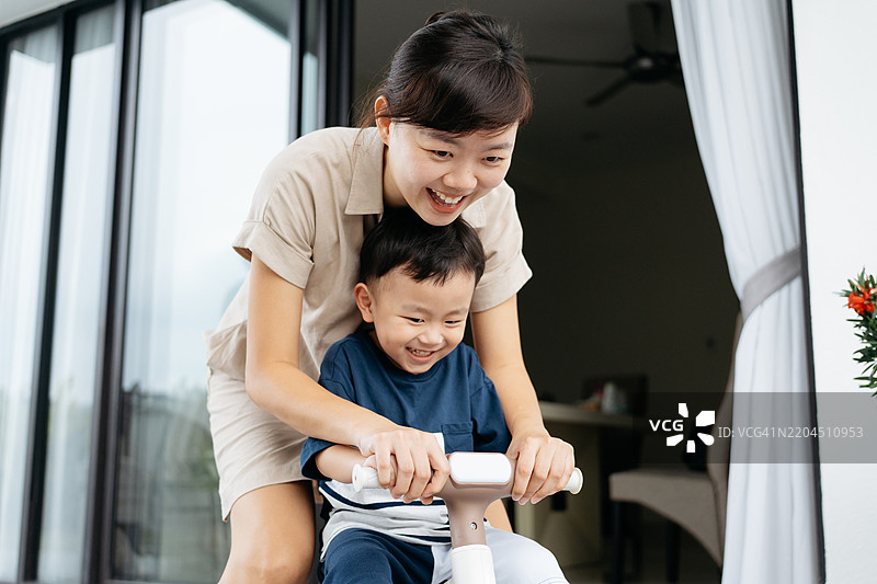 亚洲可爱男孩在后院与母亲学习骑自行车图片素材