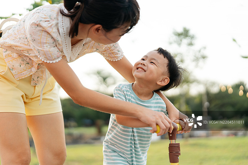 小男孩在公园里学习骑滑板车图片素材