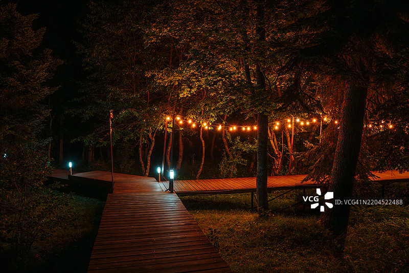 高加索山脉夜晚的木栈道上装饰着悬挂的灯泡。图片素材