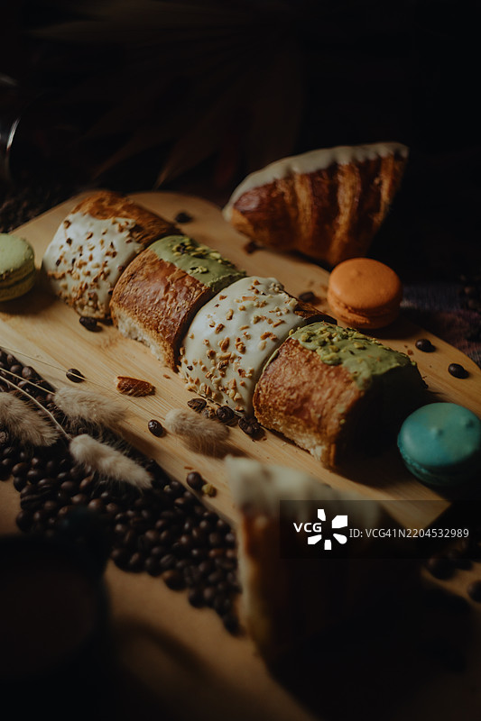 美味的糕点和马卡龙摆放在木板上，旁边是咖啡豆图片素材