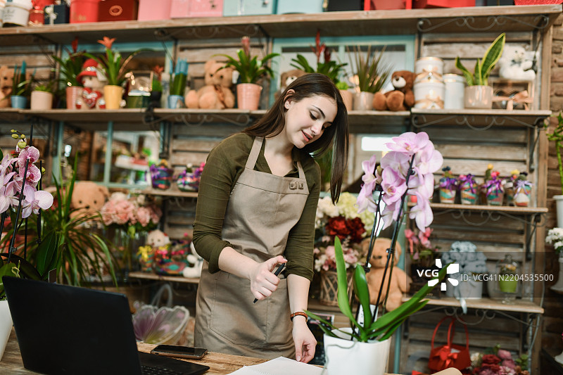 花店女员工在记事本中整理笔记和订单图片素材