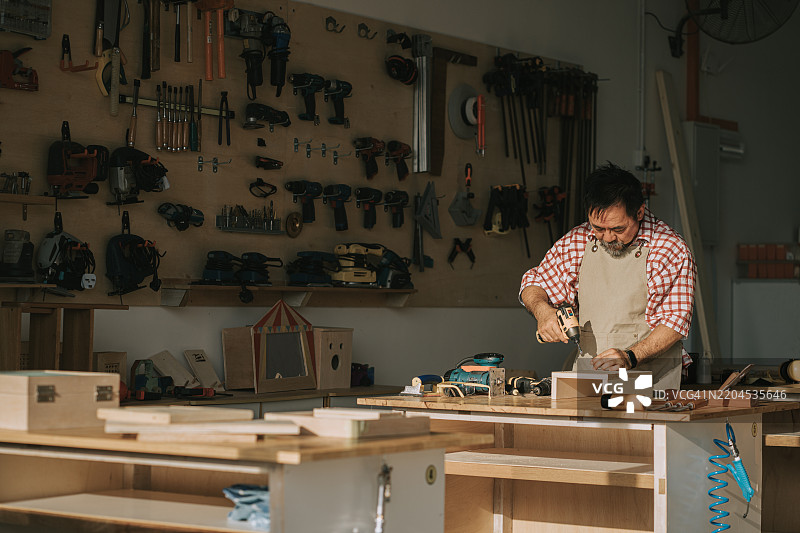 亚洲华裔老年木匠在木工车间独自工作图片素材