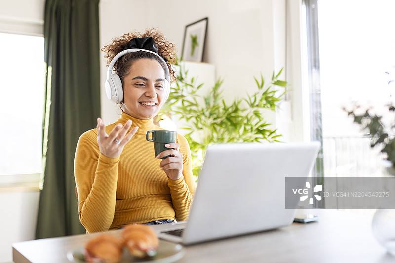 专注的女性戴着耳机在室内使用笔记本电脑工作图片素材