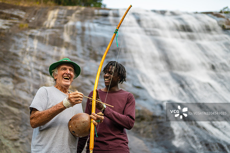 在瀑布旁演奏贝林鲍的男人们图片素材