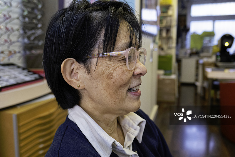 成熟的亚洲女性在法国巴黎的眼镜店微笑图片素材