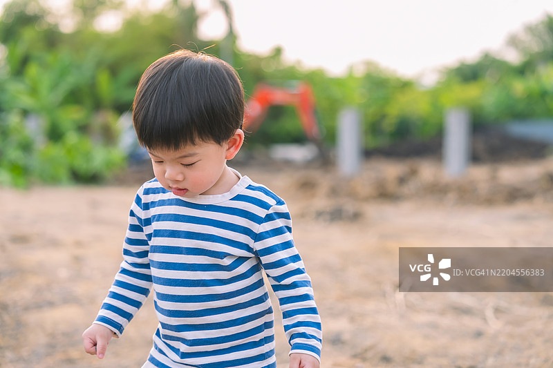 亚洲幼儿可爱的1岁8个月大的白人男孩在夏天的日落时分走在沙地公园里。体现了快乐童年和积极户外探索的概念。图片素材