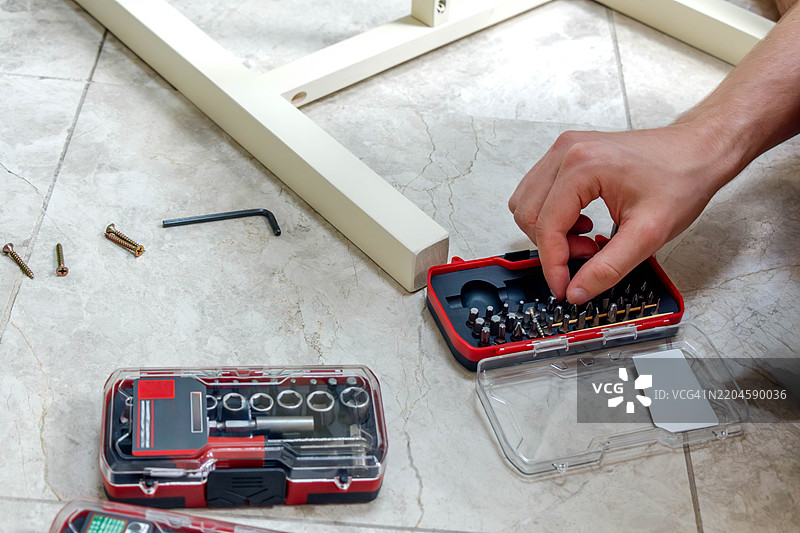 一只手从盒子里拿起一个螺丝刀头图片素材