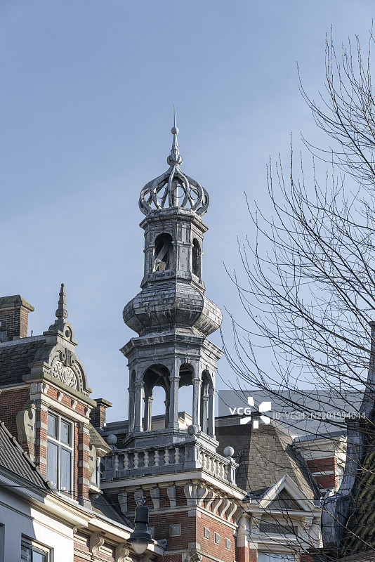 荷兰哈勒姆市的古老建筑上方耸立着尖顶教堂塔楼图片素材