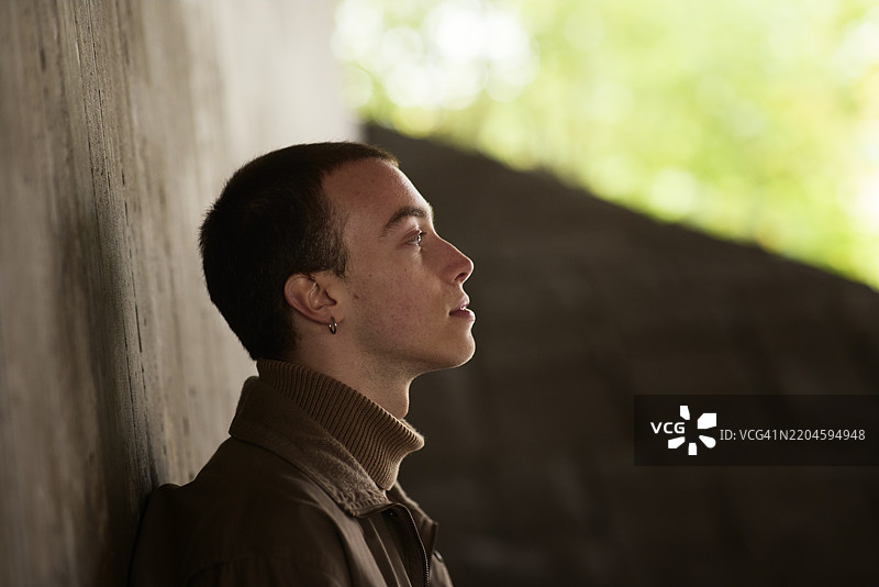 沉思的男人靠在灰色墙壁上图片素材