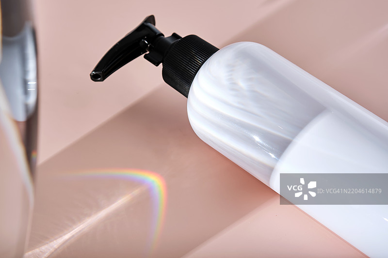 粉色粉末背景上的白色浴产品瓶子图片素材