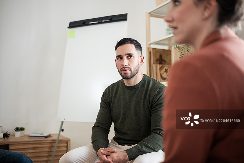 专注的年轻男性在团体治疗会议中倾听图片素材