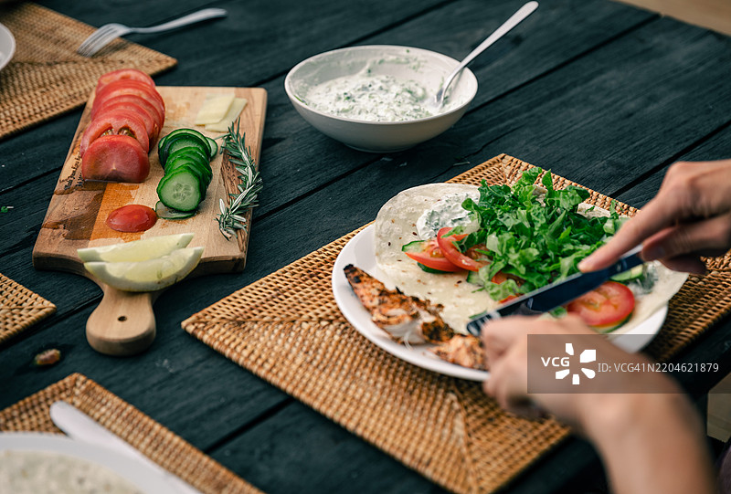 特写镜头：一位女性正在切鸡肉，为健康卷饼做准备图片素材