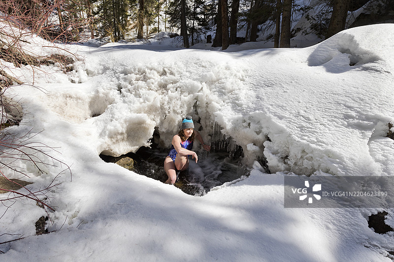 在自然雪溪中进行冷水浴的老年女性图片素材