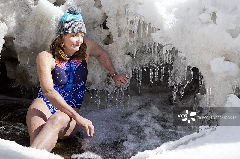 在自然雪溪中进行冷水浴的老年女性图片素材