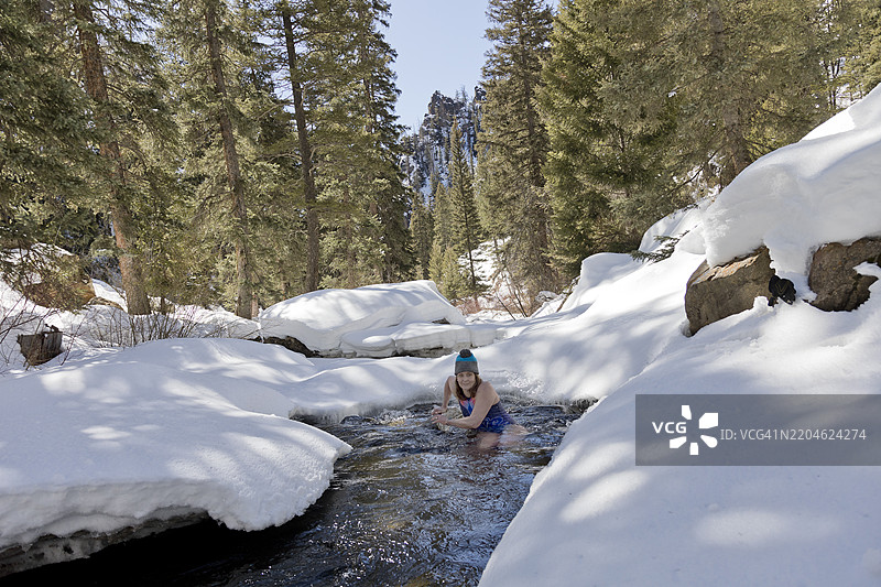 在自然雪溪中进行冷水浴的老年女性图片素材