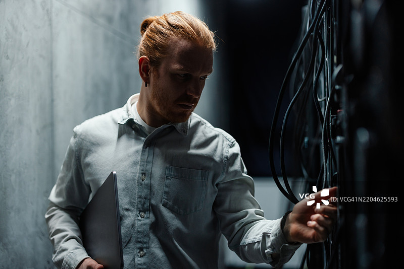 IT专家在昏暗的服务器机房检查服务器硬件图片素材