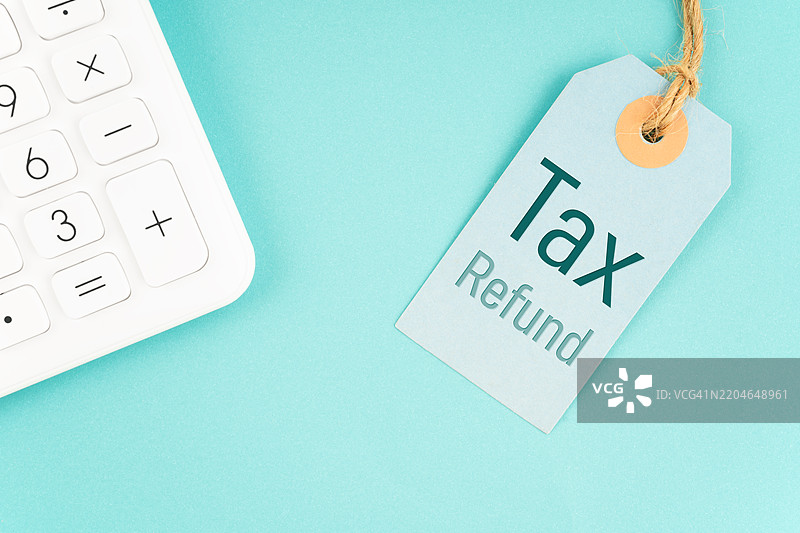 蓝色背景上的产品价格标签和计算器的税款退款。图片素材