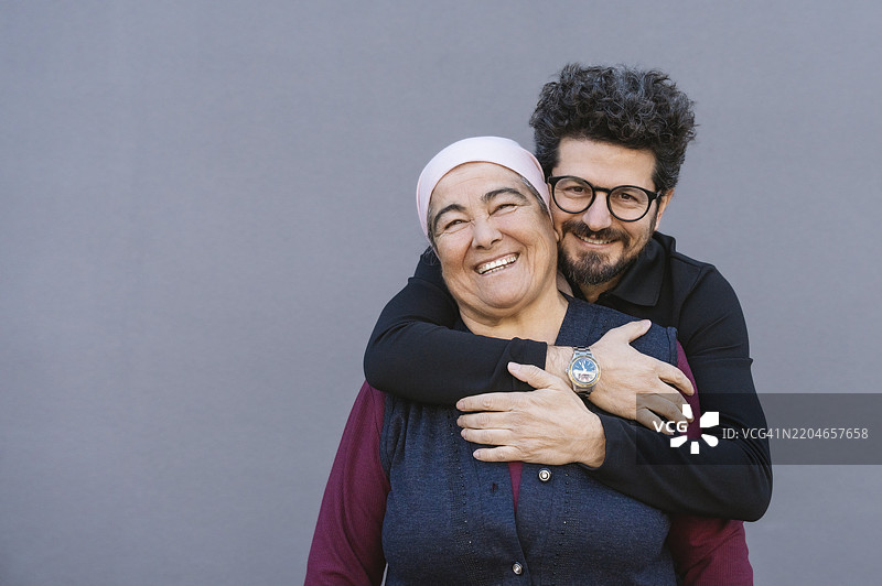 中年土耳其儿子拥抱戴头巾的母亲图片素材