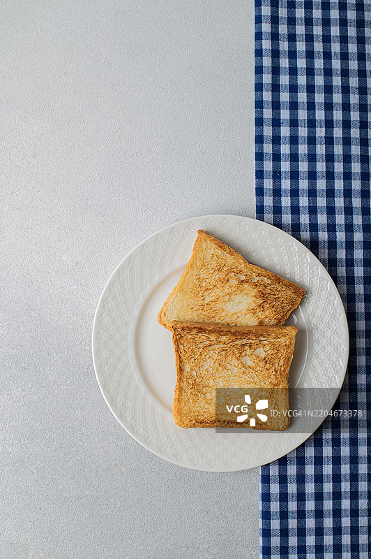 两片金黄色的吐司放在白色盘子上图片素材