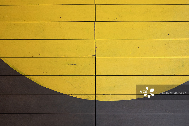 一面黄色和黑色条纹的墙壁，中间有一个大圆圈图片素材