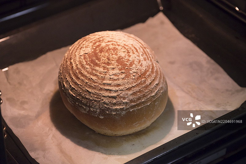 新鲜出炉的酸面包在烤箱中的烘焙纸上图片素材