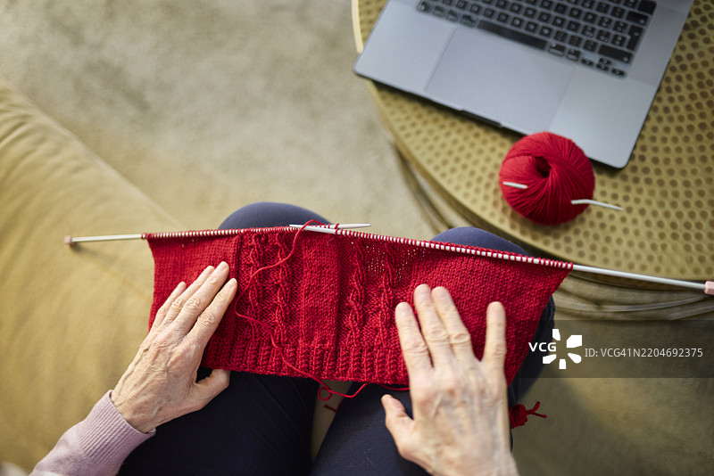 一位年长女性在家通过在线教程学习编织图片素材
